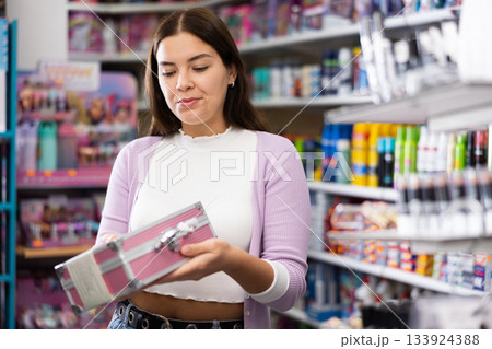 Happy woman is standing with makeup and eye shadow set in cosmetics store Happy woman is standing with makeup and eye shadow set in cosmetics store 133924388