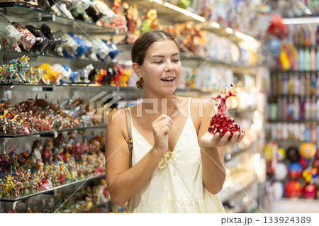 Female tourist chooses figurine of spanish dancer in souvenir shop Female tourist chooses figurine of spanish dancer in souvenir shop 133924389