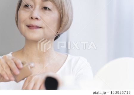 明るい窓際でメイクをするシニア女性 133925715