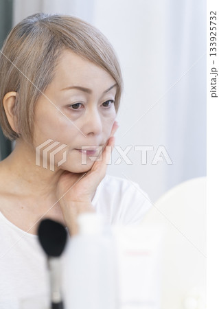 明るい窓際でメイクをするシニア女性 133925732