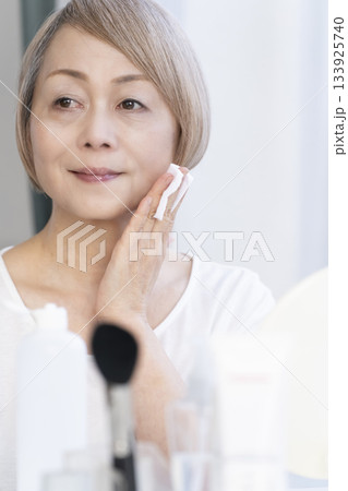 明るい窓際でメイクをするシニア女性 133925740