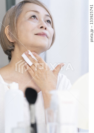 明るい窓際でメイクをするシニア女性 133925741