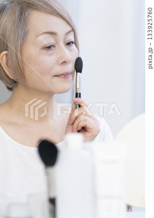 明るい窓際でメイクをするシニア女性 133925760