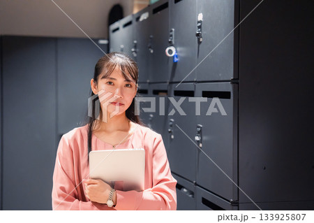 オフィスのロッカーの前でパソコンを持つ若い女性 133925807