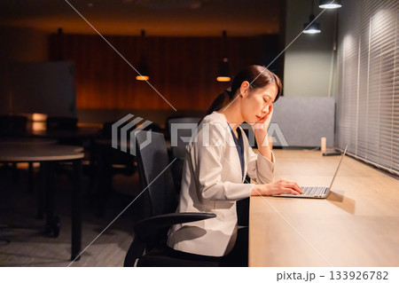 オフィスで暗くなるまで残業をして疲れる女性管理職 オフィスで暗くなるまで残業をして疲れる女性管理職 133926782