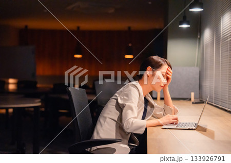 オフィスで暗くなるまで残業をして疲れる女性管理職 オフィスで暗くなるまで残業をして疲れる女性管理職 133926791