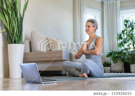 Smiling mature elderly gray-haired beautiful athletic woman doing yoga, pilates 133926833