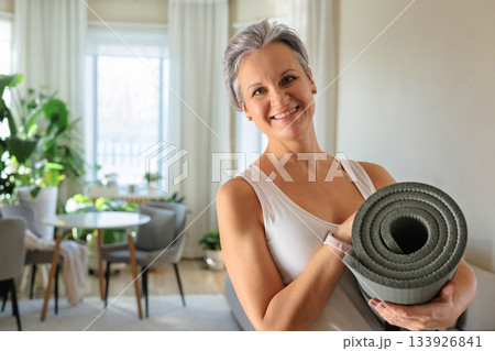 Smiling mature gray haired sport woman with yoga roll mat posing isolated. Happy mid age senior Smiling mature gray haired sport woman with yoga roll mat posing isolated. Happy mid age senior 133926841