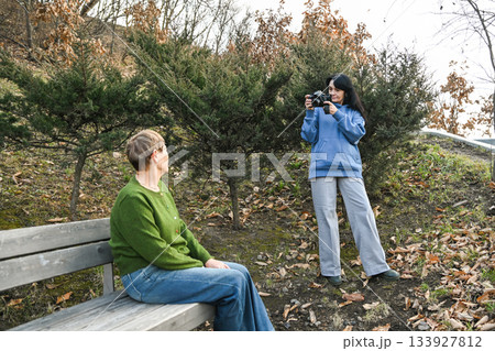 Two Russian women in their 50 years old and 60 years old enjoy an outdoor photo session, showing creativity, mindfulness, active aging and a calm supportive friendship. 133927812