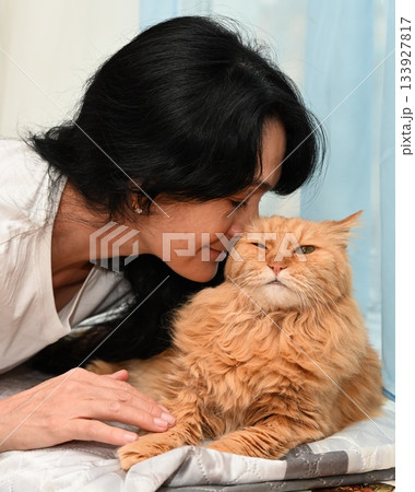 Russian woman 50 leans toward her senior cat sharing a playful mindful moment as the pet shows a funny displeased expression creating warm emotional contrast 133927817