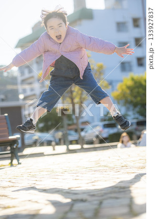 公園で大きくジャンプする幼児の女の子と元気あふれる外遊びシーン 公園で大きくジャンプする幼児の女の子と元気あふれる外遊びシーン 133927837