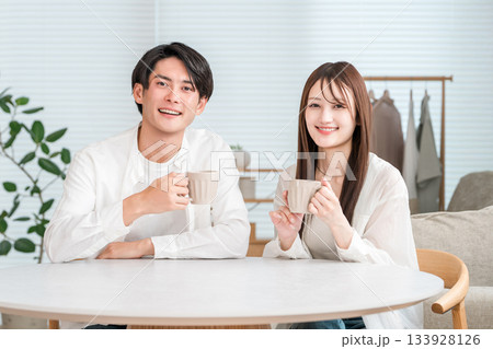 自宅のリビングでダイニングテーブルに座る若いアジア人夫婦（将来設計,ライフプラン,ライフスタイル） 133928126