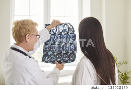 Female doctor reviewing X-ray with patient, discussing MRI results and providing medical guidance. Female doctor reviewing X-ray with patient, discussing MRI results and providing medical guidance. 133928180