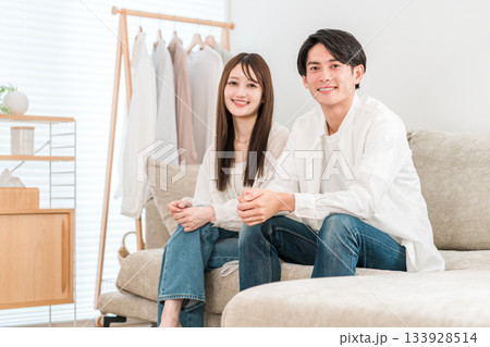 家のリビングでソファーに座る若いアジア人夫婦,カップル 133928514