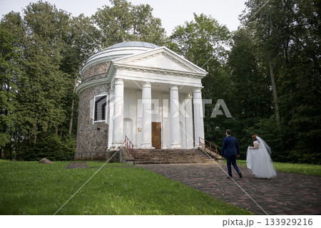 Bride and groom holding hands beside wooden fence 133929216