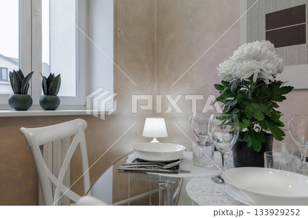 Elegant Dining Table Setting with Flowers, Glassware and Soft Interior Lighting Elegant Dining Table Setting with Flowers, Glassware and Soft Interior Lighting 133929252