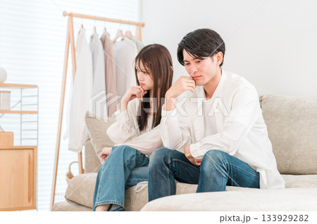 リビングのソファーに座りながら悩み事を相談する夫婦,カップルの若いアジア人 133929282