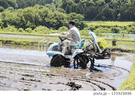 田植え機で田植えをする若い男性　米農家 133929896