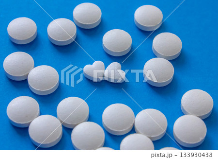 Heart shaped and round white pills on blue background. Global healthcare concept. Health and Medicine. Love concept for Valentine's day with love pills. 133930438