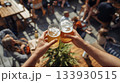 人々が集まる屋外の飲食スペースで乾杯する手 133930515