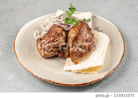 Grilled juicy pork pieces served on lavash with fresh sliced onions and herbs for restaurant menu, barbecue advertising, and food delivery promotion Grilled juicy pork pieces served on lavash with fresh sliced onions and herbs for restaurant menu, barbecue advertising, and food delivery promotion 133931075