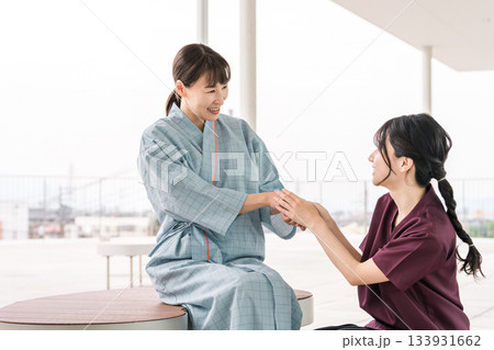 病院の屋上テラスで女性患者と会話する看護師の女性スタッフ 133931662