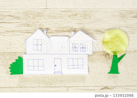 Simple paper house sketch with tree cutouts on light wooden background Simple paper house sketch with tree cutouts on light wooden background 133932098
