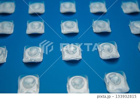 Contact lenses in disposable containers lie on a blue background at the same distance. The concept of ophthalmology, medicine, vision correction, eye care. High quality photo 133932815