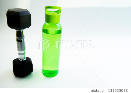 Dumbbell and water bottle are arranged on a white background, representing a healthy lifestyle, fitness motivation, and hydration for active routines Dumbbell and water bottle are arranged on a white background, representing a healthy lifestyle, fitness motivation, and hydration for active routines 133933058