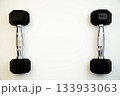 Two black dumbbells with silver accents are arranged symmetrically on a white background, emphasizing fitness and exercise with ample copy space for creative use 133933063
