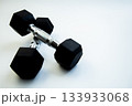 Hexagonal dumbbells with a sleek design are placed on a smooth white background, ideal for fitness enthusiasts and promoting strength training activities 133933068