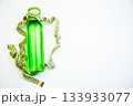A vibrant green water bottle is artistically placed with measuring tape, representing health and fitness concepts, with clear copy space for creative use 133933077