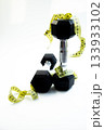 Dumbbells are artistically arranged with measuring tape on a clean surface, representing fitness and health, ideal for promoting exercise and wellness concepts 133933102