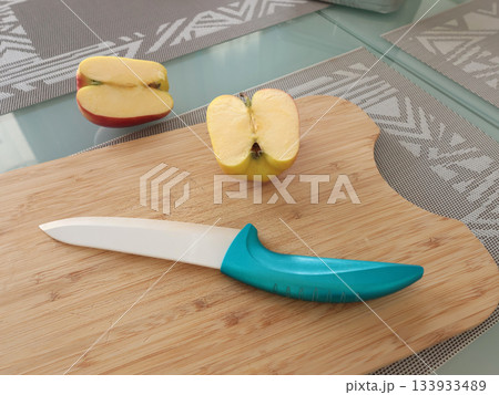 Ceramic knife and cut apple on wooden cutting board. Food and cooking. 133933489