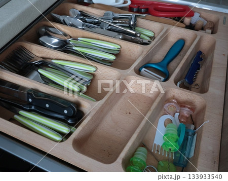 Cutlery on wooden shelf in kitchen. Storage, organization. Clean cabinets and shelves. Knives, spoons and forks, small items for everyday use. 133933540