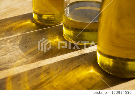 olive oil bottls with golden reflections on wooden table close up olive oil bottls with golden reflections on wooden table close up 133934550