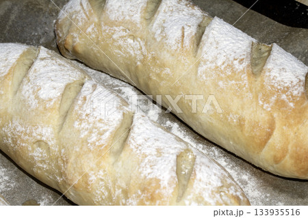 Close up of fresh homemade baguette sub rolls bread that has come out of the oven and still on baking tray Close up of fresh homemade baguette sub rolls bread that has come out of the oven and still on baking tray 133935516