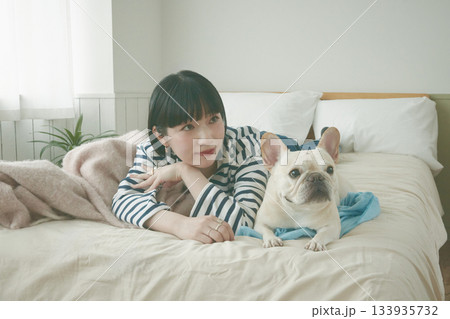 ベッドに寝そべる犬と女性 133935732