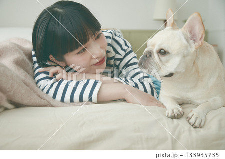 ベッドに寝そべる犬と女性 ベッドに寝そべる犬と女性 133935735