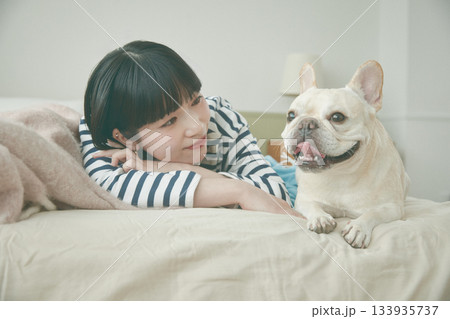 ベッドに寝そべる犬と女性 133935737