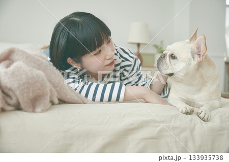 ベッドに寝そべる犬と女性 ベッドに寝そべる犬と女性 133935738