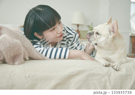 ベッドに寝そべる犬と女性 133935739