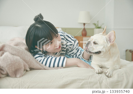 ベッドに寝そべる犬と女性 ベッドに寝そべる犬と女性 133935740