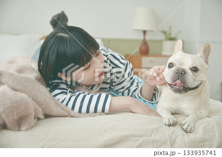 ベッドに寝そべる犬と女性 ベッドに寝そべる犬と女性 133935741