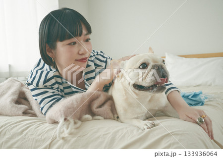 ベッドに寝そべる犬と女性 133936064