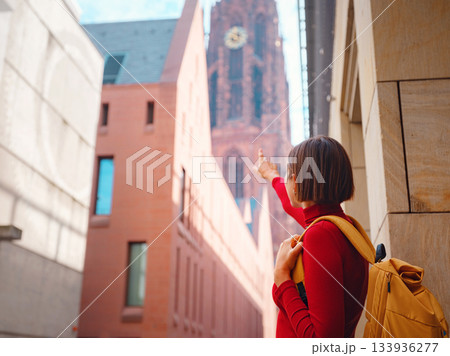 Tourist woman strolls through old town of Frankfurt, exploring its historic streets, beautiful architecture, and cultural landmarks, enjoying vibrant atmosphere of citys past. Tourist woman strolls through old town of Frankfurt, exploring its historic streets, beautiful architecture, and cultural landmarks, enjoying vibrant atmosphere of citys past. 133936277