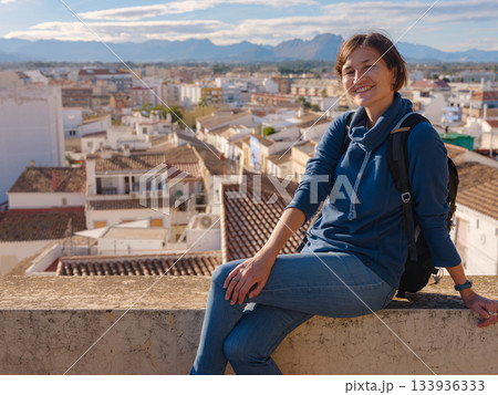 Young woman exploring historic castle in Denia, Alicante province, Spain, scenic views of town below, set against cooler season backdrop. blend of history and tranquility in timeless setting. 133936333