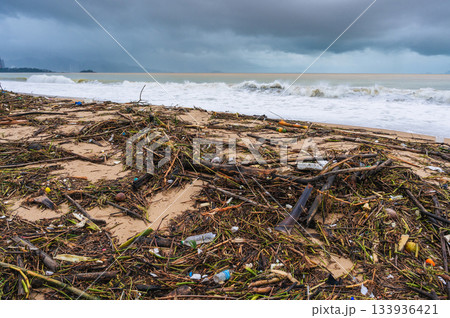 Piles of garbage and waste on beach by sea after a storm in cloudy rainy weather. Environmental disaster on waterfront of Nha Trang resort town in Vietnam 133936421
