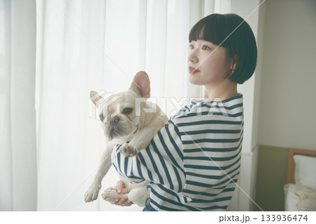 窓辺で犬を抱き抱える女性 窓辺で犬を抱き抱える女性 133936474