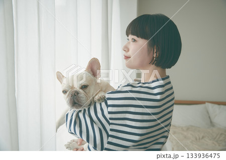 窓辺で犬を抱き抱える女性 133936475